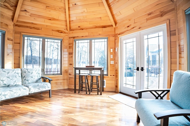 living area with french doors, wood ceiling, beam ceiling, light hardwood / wood-style floors, and wood walls