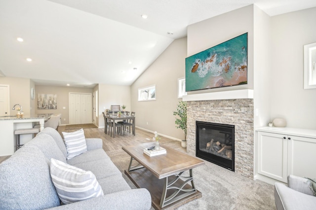 living room with lofted ceiling, a fireplace, and light hardwood / wood-style flooring