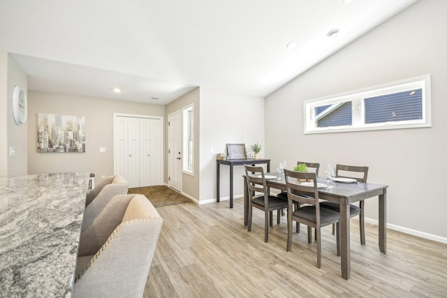 dining space with lofted ceiling and light hardwood / wood-style flooring