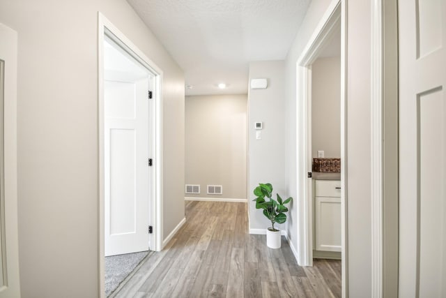 hall featuring a textured ceiling and light hardwood / wood-style floors