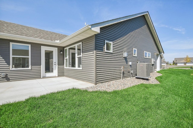 rear view of house featuring cooling unit, a lawn, and a patio