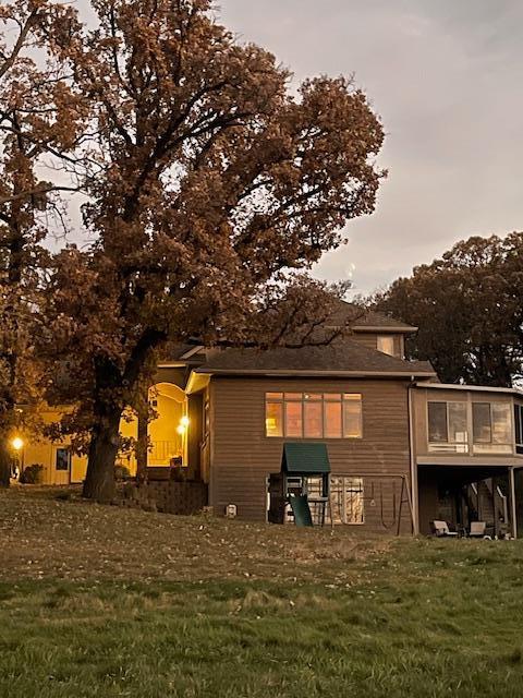 back house at dusk featuring a lawn