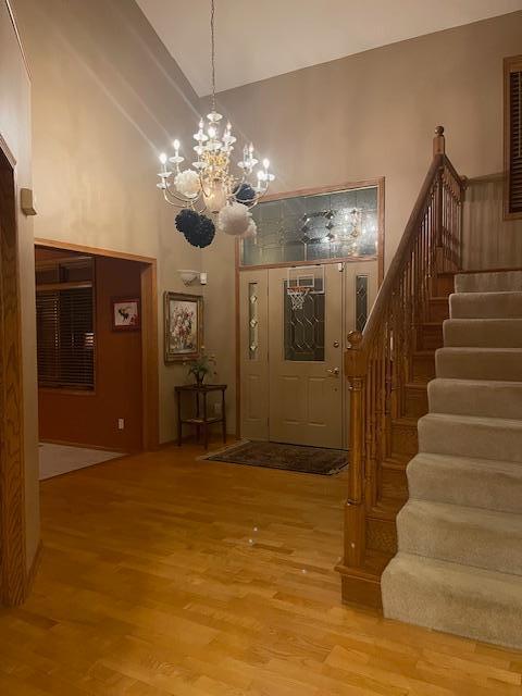 foyer featuring high vaulted ceiling, wood-type flooring, and a notable chandelier