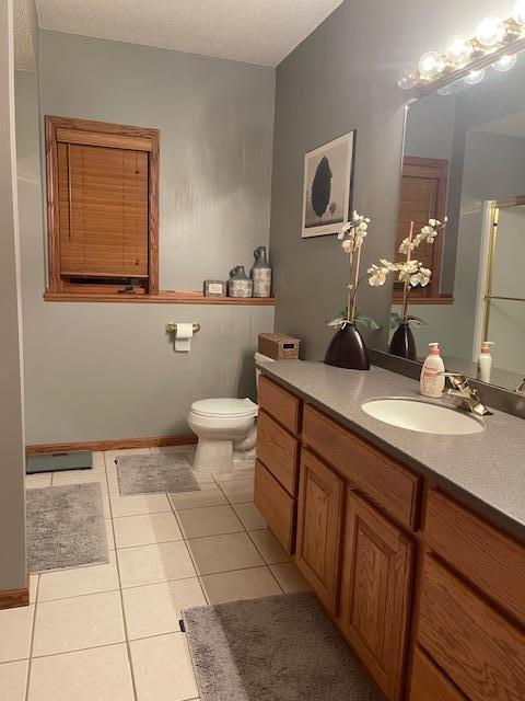 bathroom with tile patterned flooring, vanity, a textured ceiling, and toilet