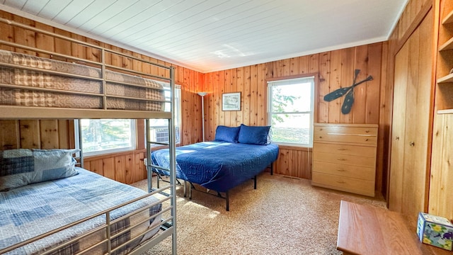 carpeted bedroom with ornamental molding and wooden walls