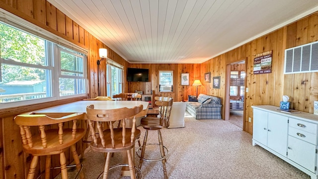 carpeted dining room with wooden walls, wooden ceiling, a wealth of natural light, and cooling unit