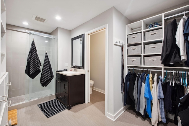 bathroom featuring toilet, visible vents, a spacious closet, and a stall shower