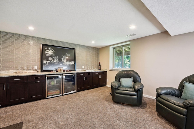 bar featuring wine cooler, wet bar, visible vents, light carpet, and baseboards