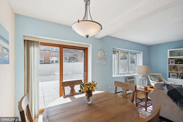 dining area with a wall mounted AC, beamed ceiling, and light tile patterned flooring