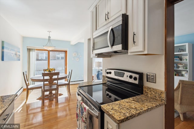 kitchen featuring light wood-type flooring, stainless steel appliances, dark stone counters, decorative light fixtures, and white cabinets