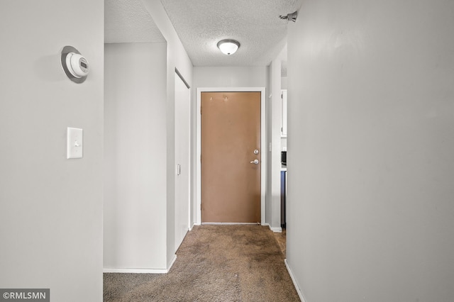 hall featuring a textured ceiling and carpet flooring