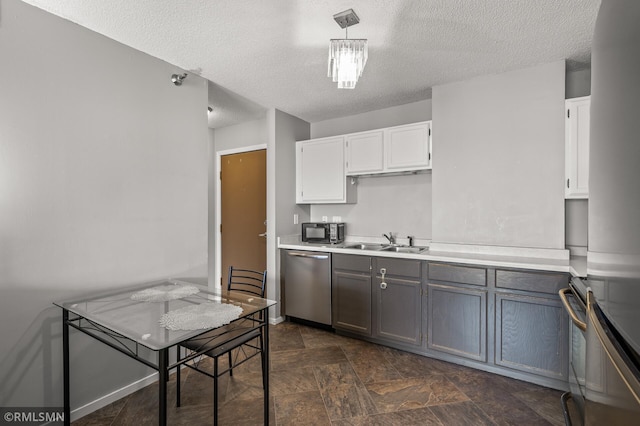 kitchen with white cabinets, stainless steel appliances, sink, and pendant lighting