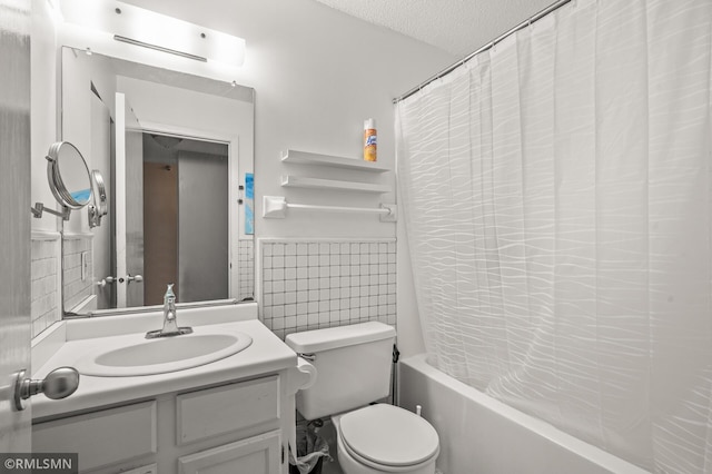 full bathroom featuring toilet, shower / bath combo with shower curtain, tile walls, vanity, and a textured ceiling