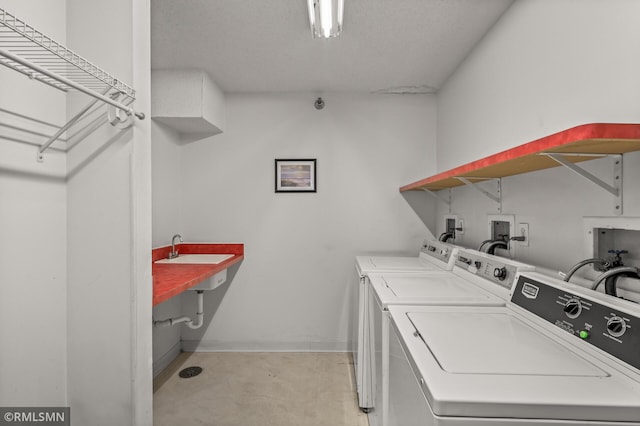 clothes washing area featuring washer and dryer, sink, and a textured ceiling