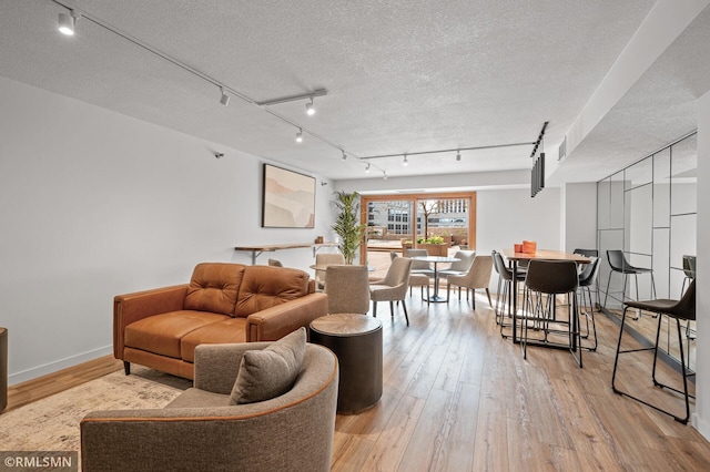 living room with light hardwood / wood-style flooring, a textured ceiling, and track lighting