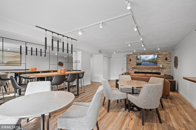 dining area featuring light hardwood / wood-style flooring, track lighting, and a fireplace