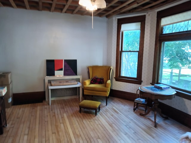 living area featuring baseboards, wallpapered walls, and hardwood / wood-style flooring