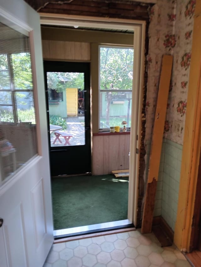 entryway with tile patterned floors, a wainscoted wall, and carpet floors
