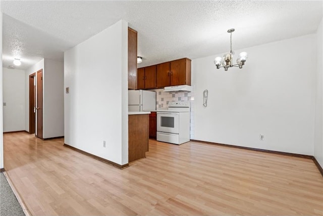 kitchen featuring white appliances, light hardwood / wood-style flooring, a notable chandelier, backsplash, and a textured ceiling