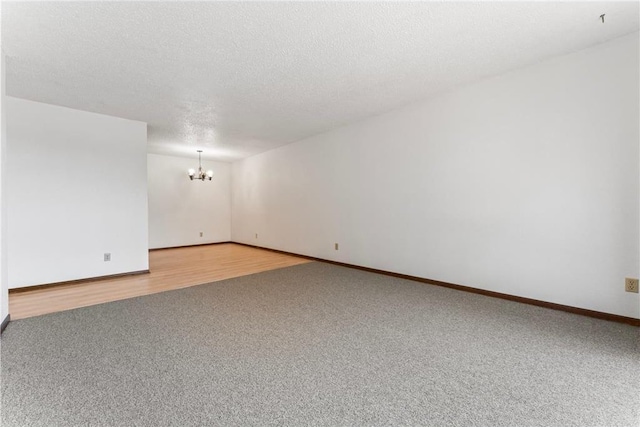 carpeted spare room with a notable chandelier and a textured ceiling