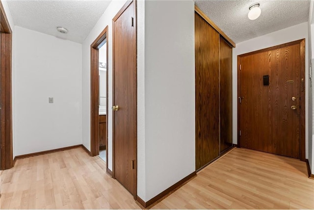 hall featuring a textured ceiling and light hardwood / wood-style flooring