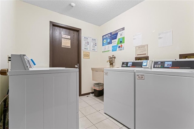 laundry area featuring independent washer and dryer, light tile patterned flooring, and a textured ceiling