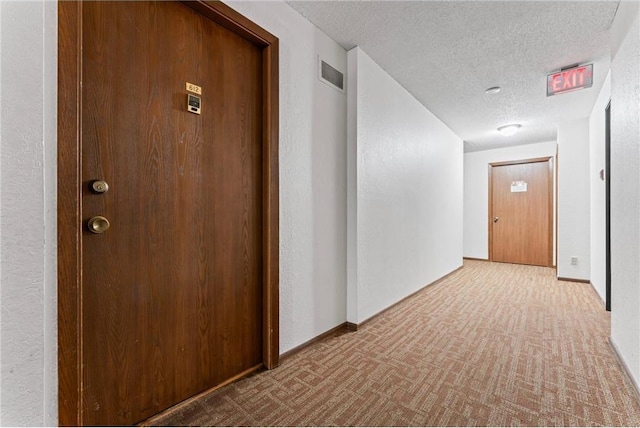 hallway featuring a textured ceiling and light colored carpet