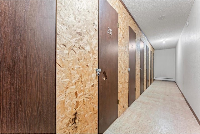 hallway with a baseboard heating unit and a textured ceiling