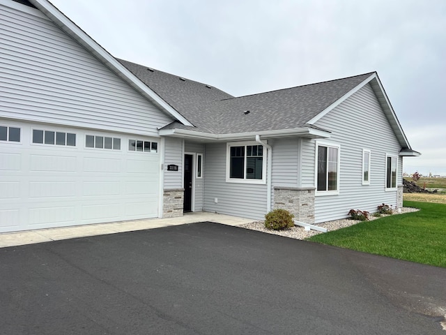 3116 Bassett Dr, Mankato, MN 56001 - ranch-style home with stone siding, an attached garage, a shingled roof, a front lawn, and driveway