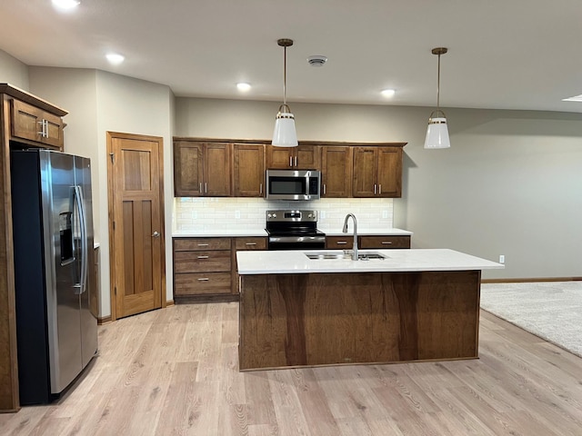 kitchen featuring decorative light fixtures, light hardwood / wood-style floors, stainless steel appliances, and sink