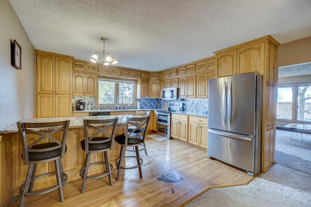 kitchen featuring tasteful backsplash, a breakfast bar, appliances with stainless steel finishes, an inviting chandelier, and a sink