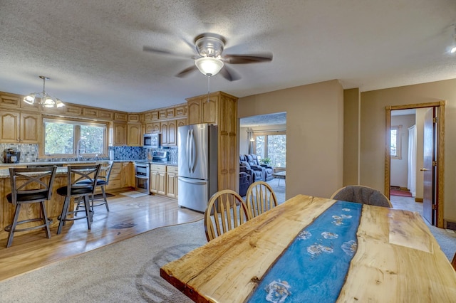 dining space featuring visible vents, a textured ceiling, a healthy amount of sunlight, and a ceiling fan