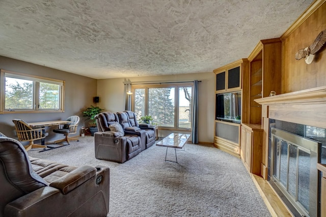 living area with light carpet, a glass covered fireplace, a healthy amount of sunlight, and a textured ceiling