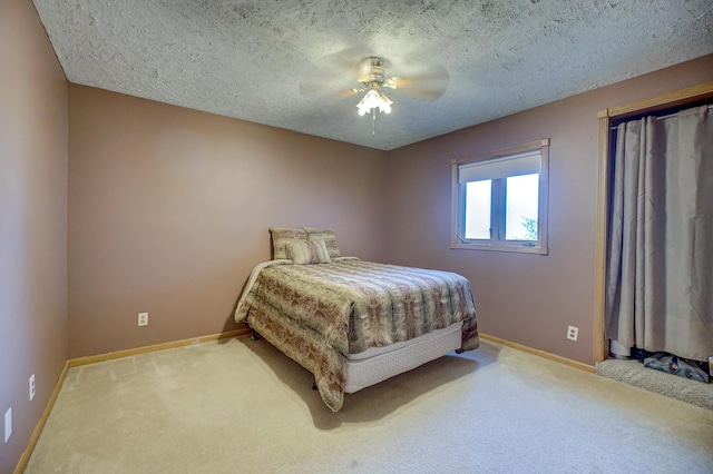 carpeted bedroom featuring a textured ceiling, baseboards, and a ceiling fan