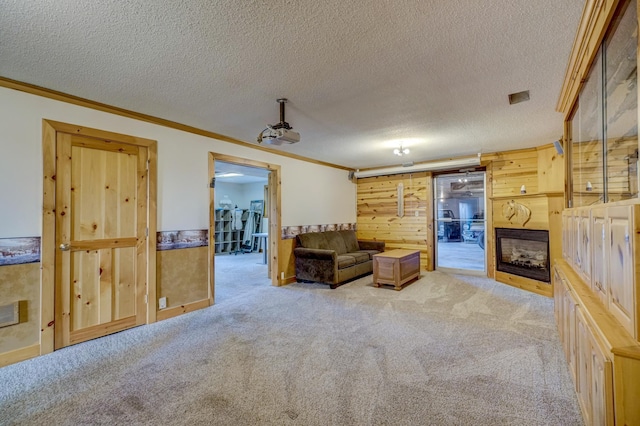 living area featuring light colored carpet, a fireplace, a textured ceiling, and crown molding