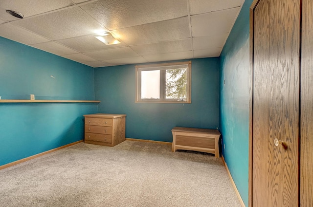 unfurnished bedroom featuring carpet flooring, baseboards, and a drop ceiling