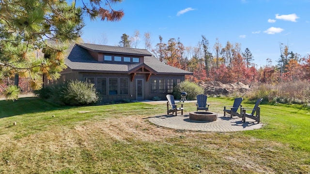 rear view of house with an outdoor fire pit, a patio area, and a lawn