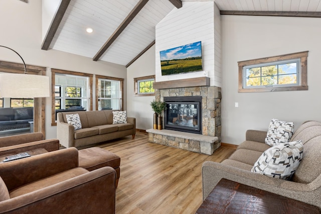 living area with wooden ceiling, baseboards, a stone fireplace, wood finished floors, and beamed ceiling