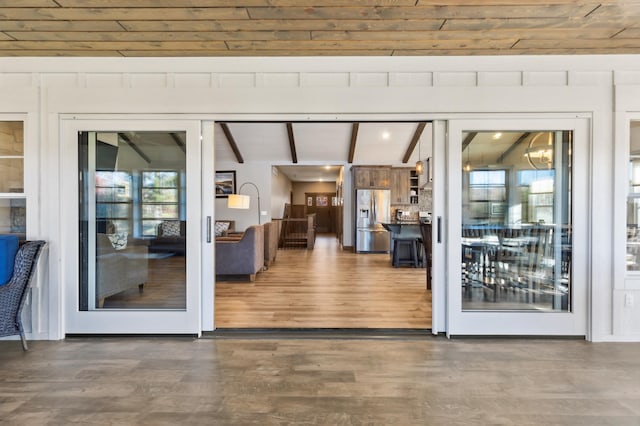 doorway to outside with wooden ceiling, wood finished floors, and vaulted ceiling with beams