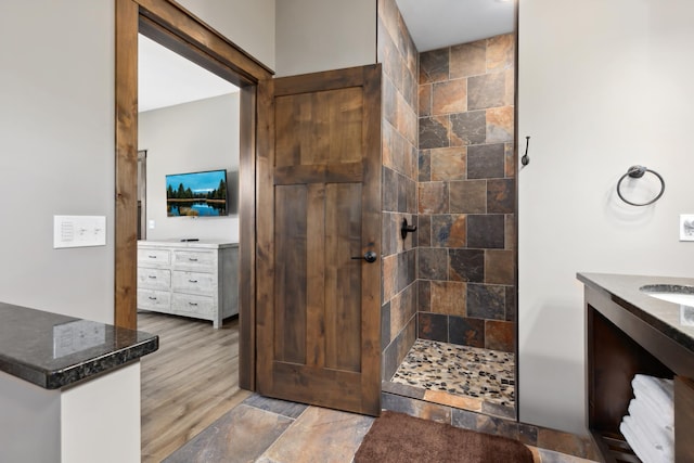 bathroom with vanity, tiled shower, and hardwood / wood-style floors