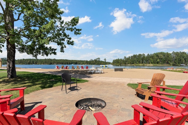 view of home's community with a patio, an outdoor fire pit, a water view, and a lawn