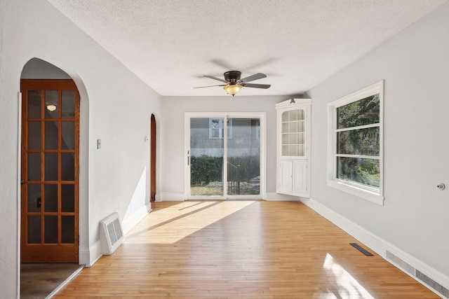 spare room with a textured ceiling, light wood-type flooring, and ceiling fan