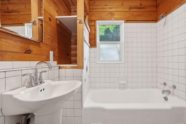 bathroom featuring tile walls, sink, wooden walls, and tiled shower / bath