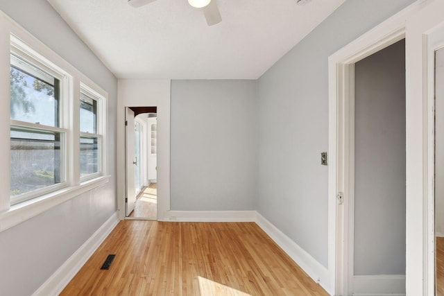 empty room with ceiling fan, light hardwood / wood-style flooring, and a healthy amount of sunlight