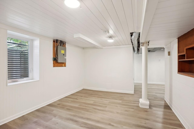 basement featuring electric panel, light hardwood / wood-style floors, and wood ceiling