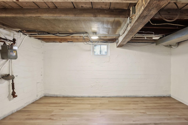 basement featuring wood-type flooring and brick wall