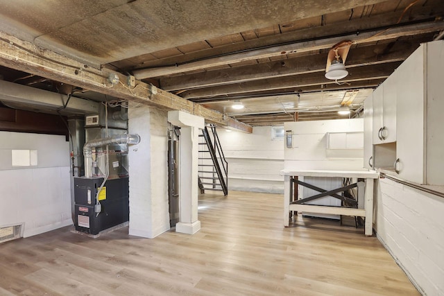 basement featuring light hardwood / wood-style flooring and heating unit