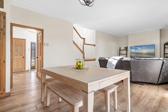 dining room with crown molding and light hardwood / wood-style flooring