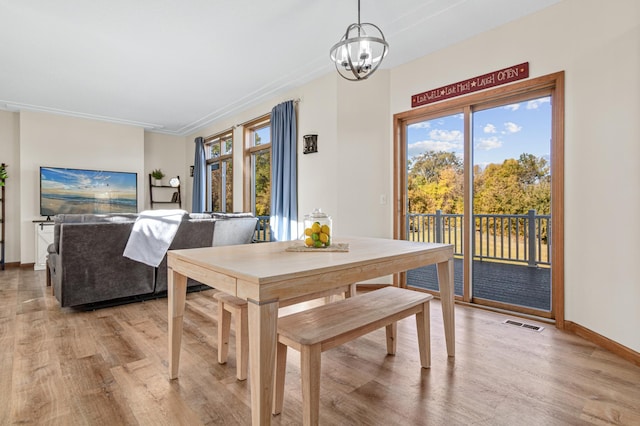 dining room featuring crown molding, a healthy amount of sunlight, light hardwood / wood-style flooring, and a chandelier