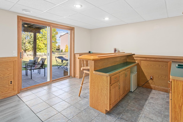 kitchen featuring a paneled ceiling, tile patterned floors, kitchen peninsula, and a kitchen breakfast bar